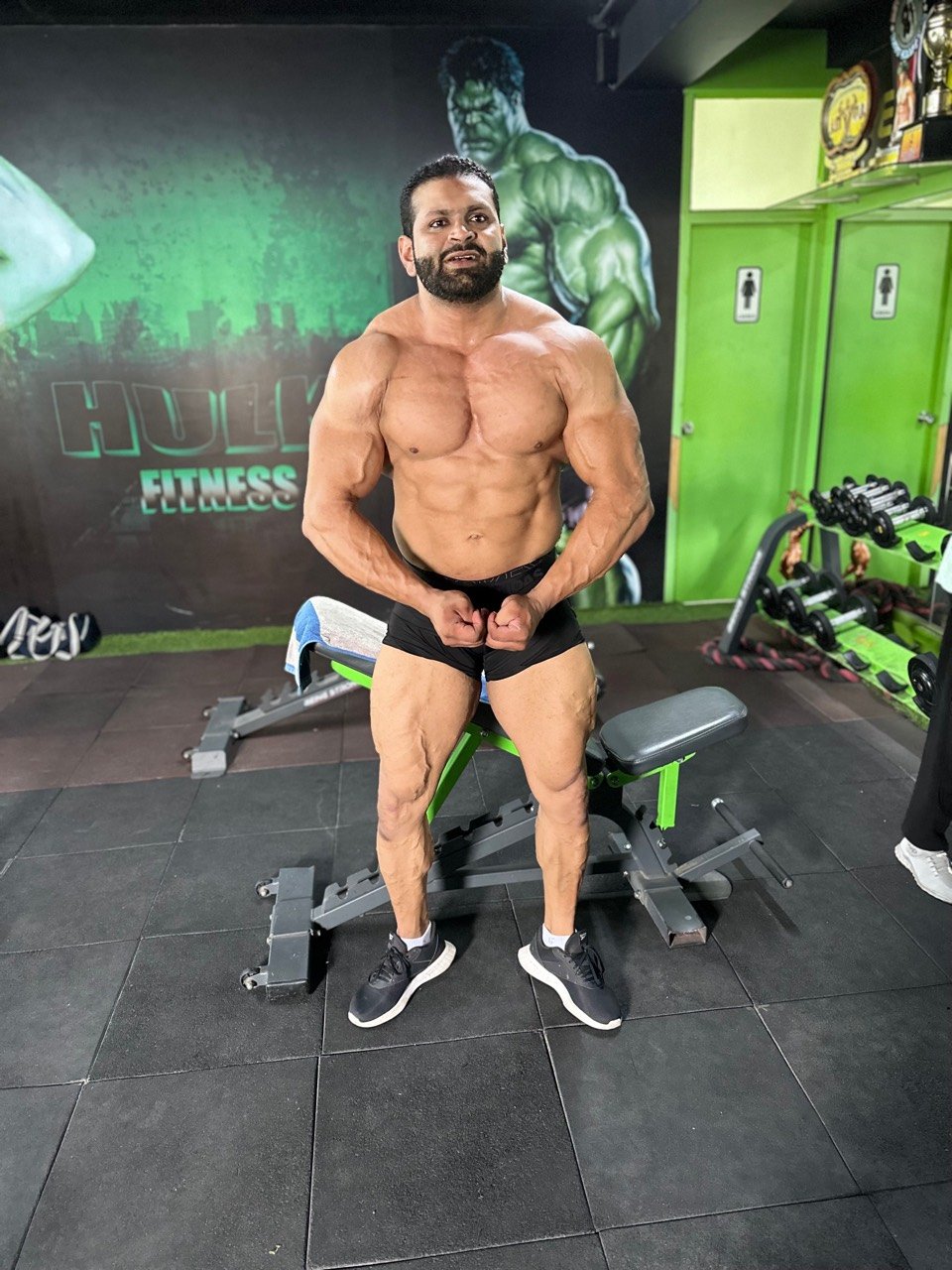Bodybuilder posing beside the Hulk Fitness mural